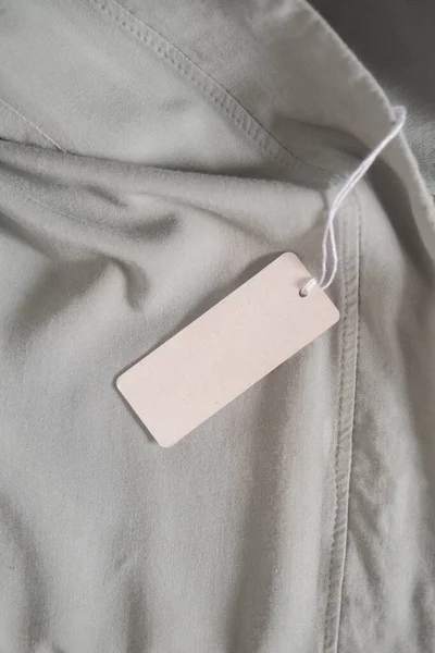 Ligh Gri Kumaş 'ta giysi etiketi. Moda markası modeli, kapat, üst görünüm, metin için boşluk kopyala
