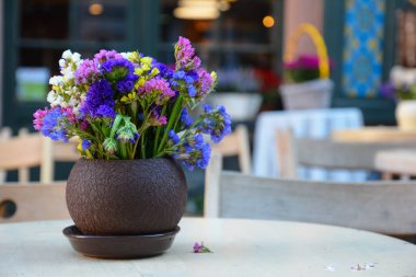 Çok renkli çiçekler vazoda sokak kafe masada dekoratif bileşimi.