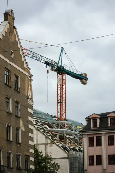 Construction crane in the center of the building. Reconstruction and construction of building in old, historic area of the city with dense buildings.