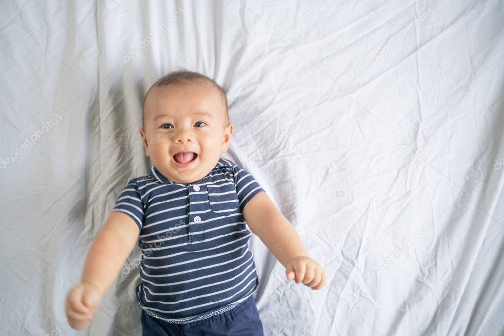 The little boy smiles in the bed in his own room