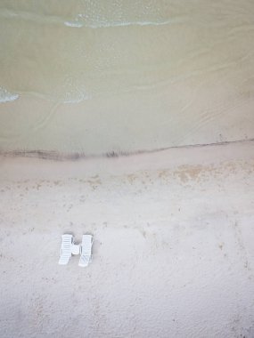 Boş plaj sandalyeleri açık mavi gökyüzüne ve okyanusa bakıyor. 