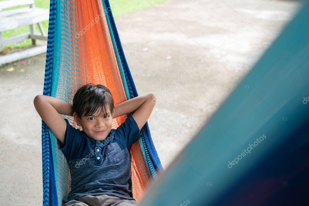 The little boy sitting at the hammock and he so happy