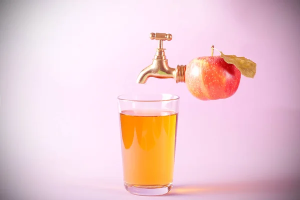 the tap in the Apple and a glass of Apple juice is on the table