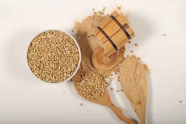 green raw buckwheat and buckwheat flour on a white background