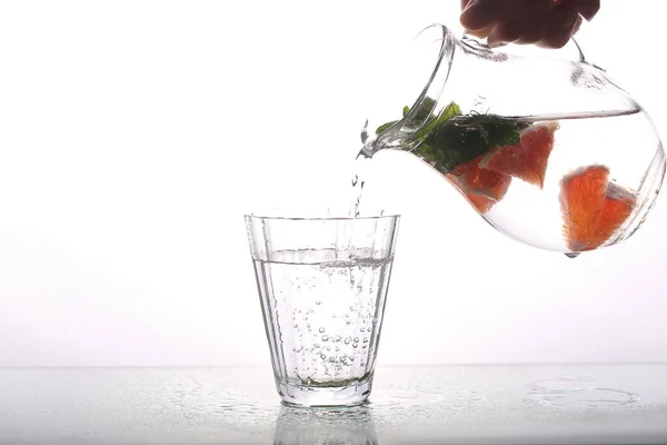 carafe of water and grapefruit on a white background