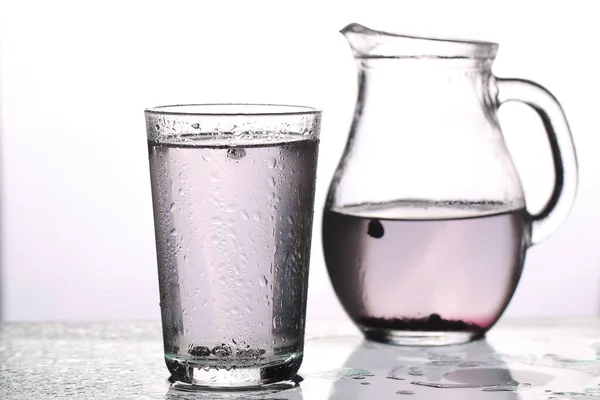 carafe of water ice and blueberries on a white background