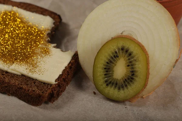 A sandwich with butter, spangles, onions and kiwi is on the table — Stock Image Sandwich Butter Spangles Onions Kiwi Table Royalty Free Stock Images