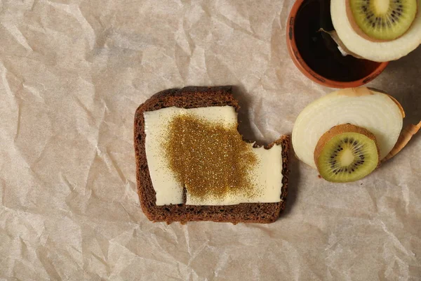 A sandwich with butter, spangles, onions and kiwi is on the table — Stock Image Sandwich Butter Spangles Onions Kiwi Table Stock Picture