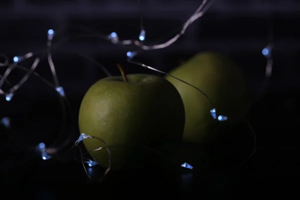 green apples on a black background with lights