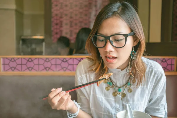 Aziatische vrouwen eten eten met stokjes in restaurants — Stockfoto