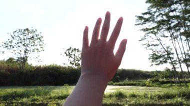 Neşeli hayalperest kız parlayan güneşe doğru elini uzatıyor. Güneşe doğru uzanan bir el.