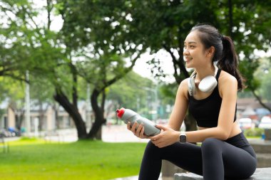 Koştuktan sonra su içen genç bir kadın. Güneşli bir günde açık havada su içen sportif bir kadın...