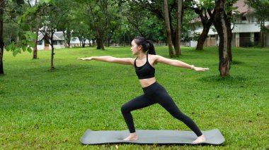 Kamu parkında yoga yapan genç bir kadın..