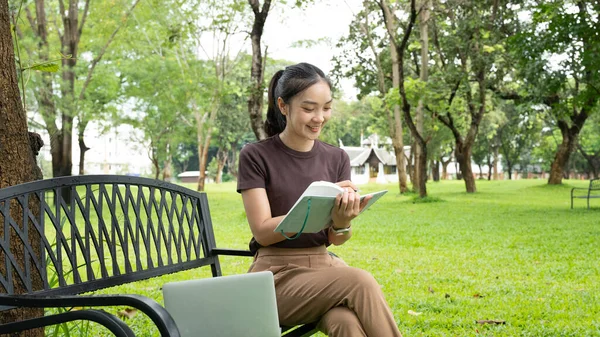 Park defterine yazan kadın. Odaklanmış genç profesyonel günlük tutma, çalışma ya da güneşli bir açık hava bankına not alma. Üretkenlik, eğitim ve refah için ideal..