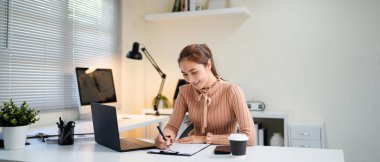 Genç iş kadını profesyonel çalışan bilgisayar kullanarak işyerinde online bankacılık analizi yapıyor. Asyalı orta yaşlı iş kadını ofiste dizüstü bilgisayarda çalışıyor, notlar alıyor. Banner, boşluğu kopyala.