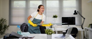 Bir ofis odasını temizlerken yeşil önlüklü bir kadın şarkı söylüyor. Elinde bir paspas var ve yaptığım işten memnun...