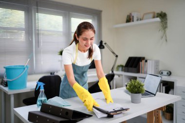 Bir ofis odasını temizlerken yeşil önlüklü bir kadın şarkı söylüyor. Elinde bir paspas var ve yaptığım işten memnun...