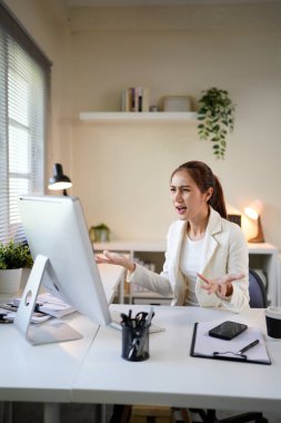 Önünde bilgisayar monitörü olan bir kadın büro masasında oturuyor. Suratı asık bir şekilde ekrana bakıyor.