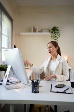 Önünde bilgisayar monitörü olan bir kadın büro masasında oturuyor. Suratı asık bir şekilde ekrana bakıyor..