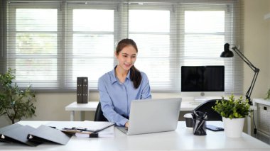 Dizüstü bilgisayarla çalışan kendine güvenen Asyalı iş kadını klavyeyi daktilo ediyor. Profesyonel yatırımcı yeni bir başlangıç projesi üzerinde çalışıyor. Ofiste iş planlama. Teknoloji işi..