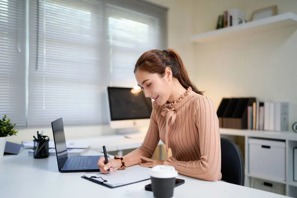 Genç iş kadını profesyonel çalışan bilgisayar kullanarak işyerinde online bankacılık analizi yapıyor. Asyalı orta yaşlı iş kadını ofiste dizüstü bilgisayarda çalışıyor, notlar alıyor. Banner, boşluğu kopyala.