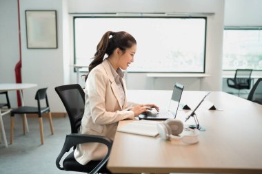 Başarılı bir iş kadını. Dizüstü bilgisayar kullanıyor, ofiste çalışıyor. İş teknolojisi kurumsal kavram.