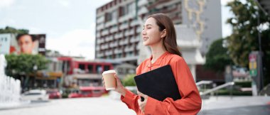 Happy, kadın dizüstü bilgisayarla yürürken kahveden hoşlanıyor. Şehir hayatı, iş öncesi şehirde kahve molası..