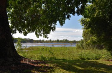 Göl Jabiru kuru sezonu bulutlu bir günde. Jabiru ana İlçesi'nde Kakadu Milli Parkı'nda var. Yeşil çim göl çevresinde.