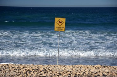 Sydney, Avustralya - 5 Temmuz 2018. Bir işaret Dangerous geçerli okur. Fırtına sonra sahilde yüzme bayrak.