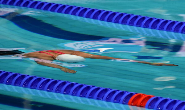 Женщины соревнуются в бассейне. Женщины плавают под водой в стиле дельфинов. Пловец в бассейне
.