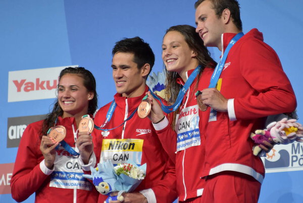 Будапешт, Венгрия - 26 июля 2017 г. Команда Канады (MASSE Кайли Жаклин, FUNK Richard, OLEKSIAK Penny, KISIL Yuri) на церемонии Победы в смешанной эстафете 4x100m Medley. Чемпионат мира по плаванию
.