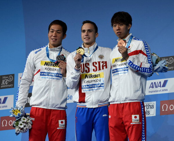 Будапешт, Венгрия - 28 июля 2017 г. ВАТАНАБЕ ИППЕЙ (Япония), КОСЕКИ ЯСУХИРО (Япония) и победитель ЧУПКОВ (Россия) на дистанции 200 м брассом. Чемпионат мира по плаванию
.