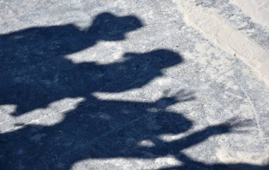 Öğleden sonra güneş ışığı altında sahilde insan siluetleri.