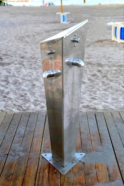 Public foot washing station wooden decking on a sandy beach, for removing sand from hands and feet