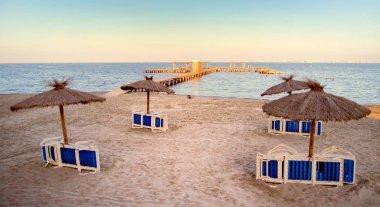 Deniz, büyük iskele girecek birlikte ıssız bir kumsala doğal hasır şemsiye banyo sıcak akşam güneşiyle - metin için yer