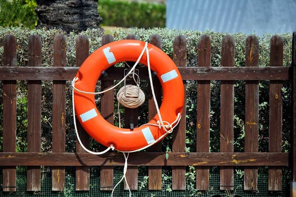 Parlak kırmızı yeleğini veya can simidi yüzdürme yardım, parlak güneş ışığı dışında ahşap bir çit bağlı