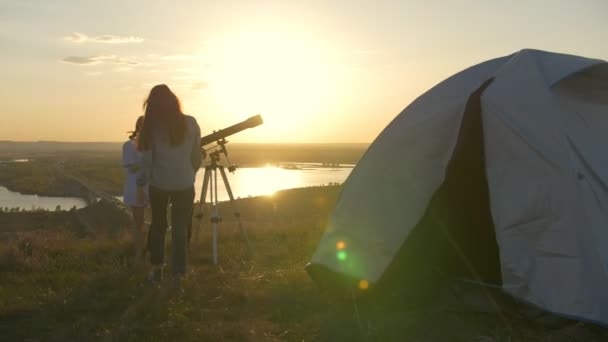 Fiatal pár hívás barátjuk, nézegette a távcső a naplemente, a hegyen — Stock videók