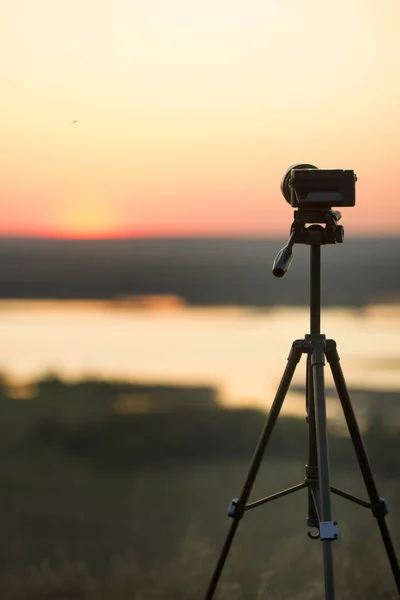 Caméra debout sur trépied sur la colline au coucher du soleil d'été — Photo