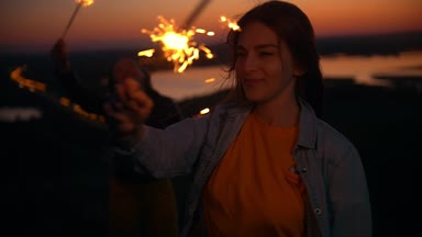 Neşeli genç kadın havai fişekleri yaz günbatımı, yavaş hareket, bir tepe üzerinde eğlenin