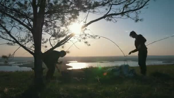 Deux jeunes hommes mettent sur la tente sur la colline au coucher du soleil — Video