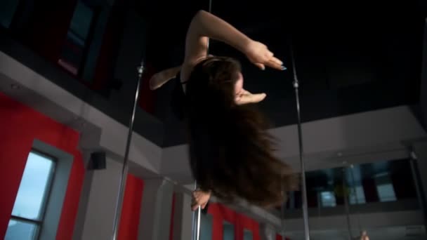 Jeune femme avec une silhouette attrayante exécutant pole dance dans un studio — Video