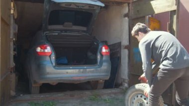 Genç adam bir tekerlek araba garaj bagaja koyar
