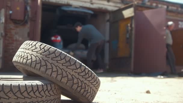 El hombre descarga los neumáticos del maletero del coche en el garaje — Vídeos de Stock