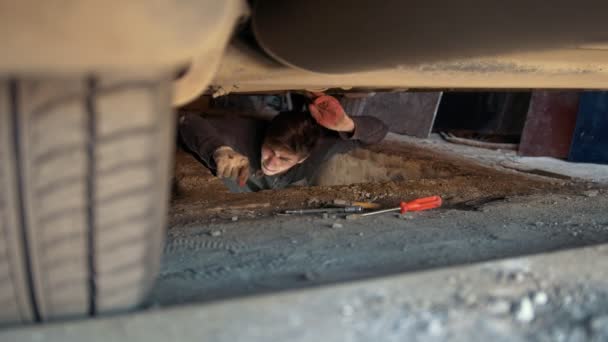 Uomo sotto un'auto che cerca un cacciavite per riparare l'auto — Video Stock