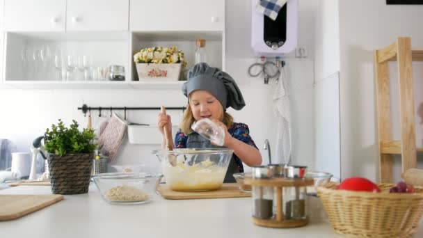 Little girl adds oatmeal to the pastry dough — Stock Video