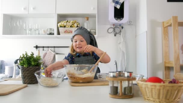 Маленькая девочка добавляет ингредиенты в тесто — стоковое видео