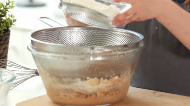 Küçük kız baker un bir elek ile sifts.