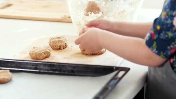 Menina pré-escolar padeiro coloca biscoitos caseiros em uma assadeira — Vídeo de Stock