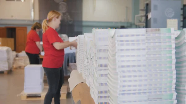 Montones de edición impresa delante de la mujer trabajadora ordenan los periódicos en la tipografía — Foto de Stock