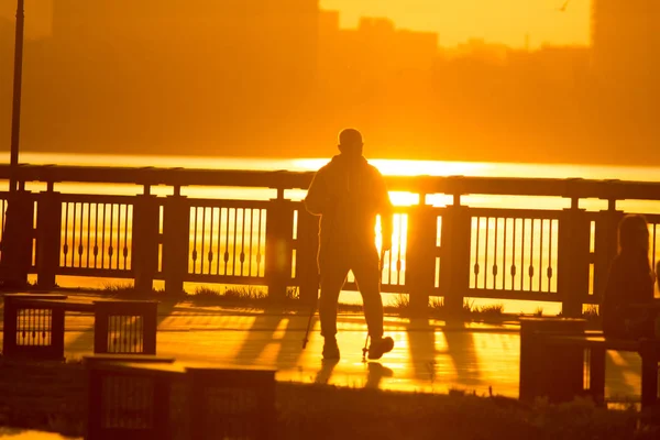Силуэт мужчины занимающегося спортом гуляющего по набережной на закате — стоковое фото